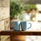 Blue mugs with hot drink on wooden table top. Blurred background.