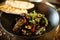 Blue mussels in white wine sauce in black bowl. Delicious healthy seafood closeup served on a table for lunch in modern