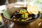 Blue mussels in white wine sauce in black bowl. Delicious healthy seafood closeup served on a table for lunch in modern