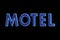 Blue neon motel sign lit up at night, isolated on black, large detailed horizontal signage closeup