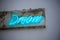 Blue neon sign Dream on a grimy wall