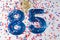 Blue number 85 with colorful confetti