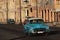 Blue old American car in a Malecon sunset