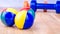 Blue and orange dumbbells and coloured balls on wooden surface