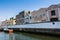 blue and orange rowing boat on the canal in Aveiro, Portugal. traditional houses on the waterfront along the canal