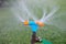 Blue and orange sprinkler watering grass. Garden irrigation system watering lawn. Closeup image of a garden sprinkler on