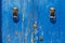 Blue painted aged wooden door with old bronze handles and locks in Rimini, Italy.