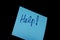 Blue paper post it note with Help message handwritten front view isolated on black