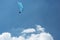 Blue Paraglider flying into the sky with clouds on a sunny day