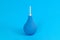 Blue pear-shaped enema with white tip on light blue background. Colon cleansing concept. Background for medical