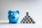 blue piggy money bank with coins pyramid, step up growing business to success and saving for retirement concept