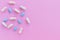 Blue pills and white capsules isolated on light pink background. Woman health. Epidemic, painkillers, healthcare and treatment