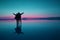 Blue and pink colored silhouette of happy couple opening arms on the flooding surface of Uyuni salt flats at