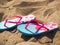 Blue and pink flip flops on sandy beach