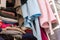 Blue and pink house robes hanging above folded, stacked and messy woman`s closet, in need of closet organization. Depicting tidyin