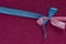 Blue and pink ribbons in the shape of a bow on a purple background. Congratulatory postcard. Copy space