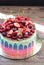 Blue, pink and violet striped cake with melted chocolate, fresh cheeries, strawberries, raspberries and mini donuts