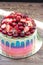 Blue, pink and violet striped cake with melted chocolate, fresh cheeries, strawberries, raspberries and mini donuts