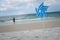 Blue pinwheel toy spinning on white sand beach, colorful wind turbine windmill on the beach with summer sea and blue sky as