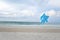 Blue pinwheel toy spinning on white sand beach, colorful wind turbine windmill on the beach with summer sea and blue sky as