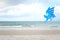 Blue pinwheel toy spinning on white sand beach, colorful wind turbine windmill on the beach with summer sea and blue sky as