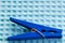 Blue plastic clothespin on a blue background. A device for holding and fixing the clothes in the drying process