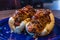Blue plate with Chili dogs in it on a wooden table under the lights with a blurry background