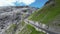 Blue Porsche 911 convertible drives on Stelvio Pass road with mountain alps panorama