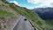 Blue Porsche 911 convertible drives up the hill on Stelvio Pass road a serpentine with mountain alps panorama.