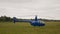 Blue private helicopter on the grass against a cloudy sky