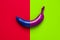 Blue and purple banana on red and green paper, abstract concept