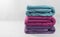 Blue, purple and pink towels arranged in a row on the white surface