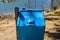 Blue recycle bin along lakeside hiking trail