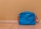 Blue with red messenger school bag isolated in against a wall and standing on the floor in a room