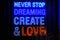 Blue and Red neon light lettering `Never stop dreaming create and love` in dark, restaurant or cafe. Front view, closeup