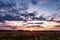 Blue red sky background with evening fluffy curly rolling clouds with setting sun. Good windy weather