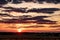 Blue red sky background with evening fluffy curly rolling clouds with setting sun. Good windy weather