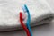 Blue and red toothbrushes in hug laying on white towel, romantic valentines day concept or couple in love in welness hotel