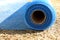 The blue reinforced mesh rolled into a roll lies on the ground. Construction resource to strengthen the walls in the process of