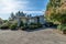 Blue residential real estate exterior home with concrete driveway and green tree blue sky