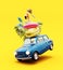 Blue retro car jumping with luggage and summer accessories on vibrant yellow background.