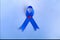 Blue ribbon on blue background with copy space. Colorectal Cancer Awareness. Colon cancer of older person. World diabetes day.