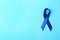 Blue ribbon on color background, top view. Colon cancer awareness concept