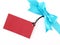 blue ribbon with simple tied bow wrapped gift box corner with blank red cardboard tag card for greeting message