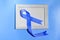 Blue ribbon with white frame on blue background with copy space. Colorectal Cancer Awareness. Colon cancer of older person. World