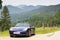 Blue roadster Porsche Boxster 986 with Bavarian Alps panorama at German Alpine Road.