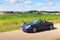 Blue roadster Porsche Boxster 986 with corn field panorama at Romantic Road