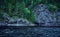 Blue rocky shore with pine trees. Background for travel materials