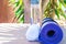 Blue Rolled Yoga Mat Bottle with Water White Towel on Greenery Palm Tree Nature Background. Sunlight. Relaxation Summer Meditation