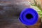 Blue rolled yoga mat lying on wooden background with green palm leaf. Fitness harmony meditation workout retreat concept